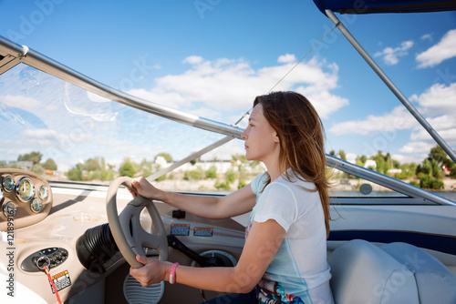 Woman behind the wheel yacht, enjoying nature and river landscape, active sailor girl, female driving luxury water transport, summertime concept. photo