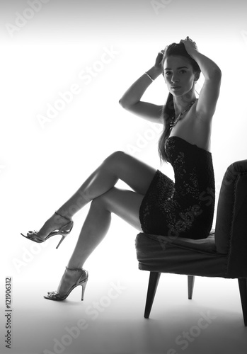 Beautiful sitting woman in studio with high heel shoes, white background