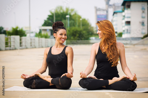Two beautiful women doing yoga outdoors in an urban neighbourhoo
