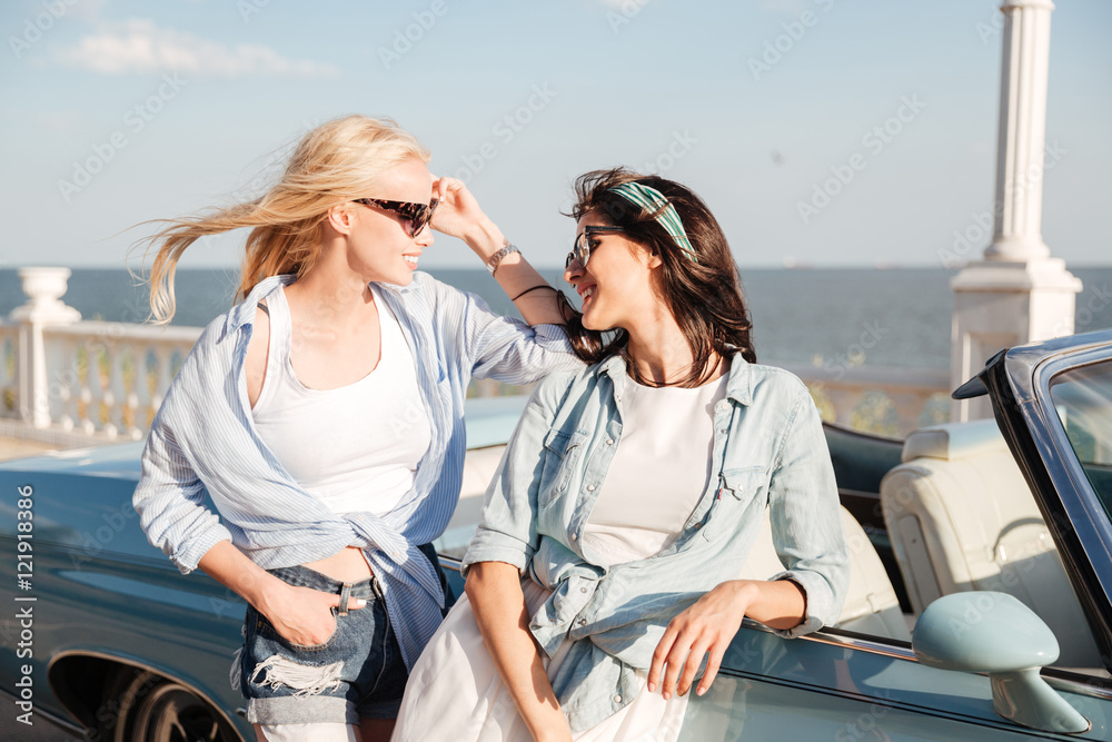 Two happy women standing and talking near cabriolet