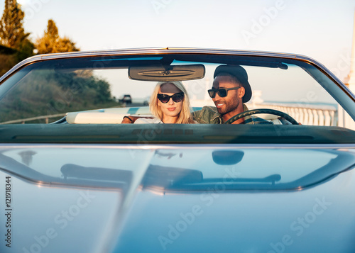Beautiful young couple sitting and driving cabriolet