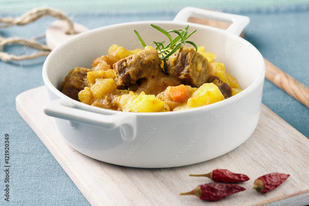 Sicilian stew in a white pot on a blue table, pastel color Sicilian stew in a white pot on a blue table, pastel color