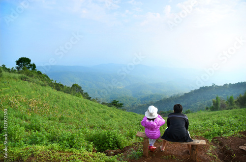 young Asian girl and boy sitting on a chair with mountain view in Maerim, Chiangmai, north of Thailand photo