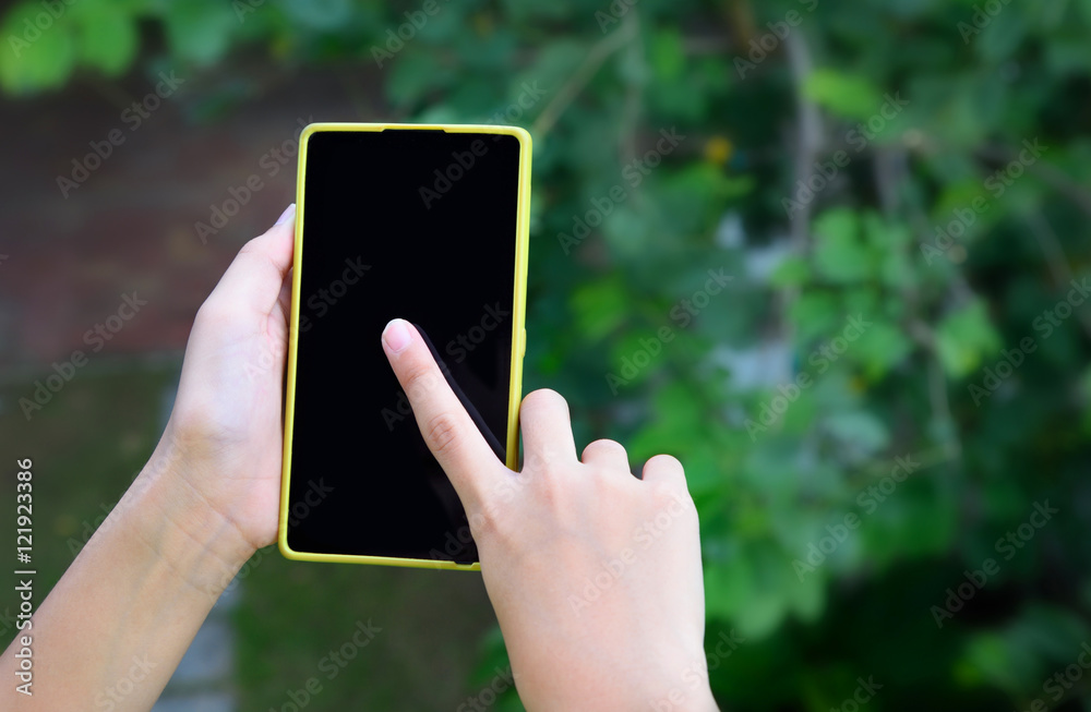 Closeup shot of girl's hand holding mobile phone. Girl using smart phone outdoor. Shallow depth of field with focus on hand holding cellphone. Close up of touch screen of smart phone. 