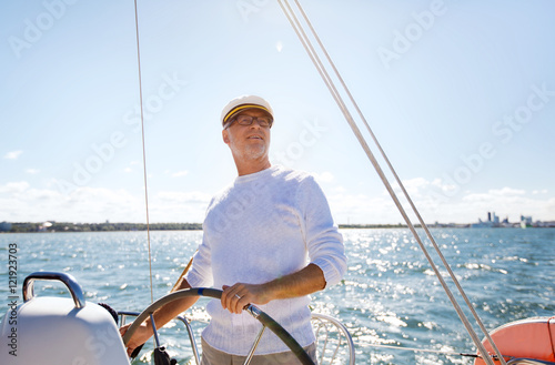 senior man at helm on boat or yacht sailing in sea © Syda Productions