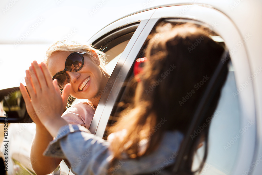 Naklejka premium happy teenage girls or women in car at seaside