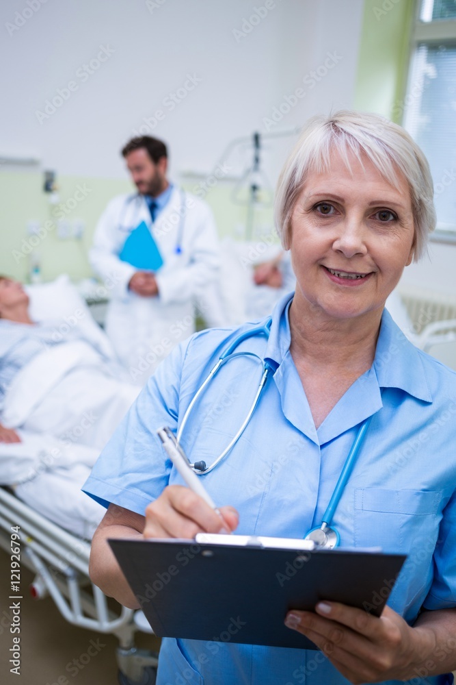Portrait of smiling nurse writing on clipboard Portrait of smiling nurse writing on clipboard