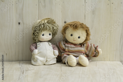 Stuffed two girls doll sitting on a wooden floor.