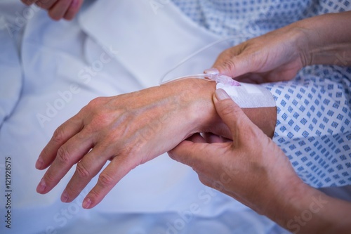 Nurse attaching iv drip on patient s hand