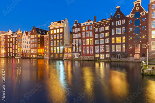 Beautiful typical Dutch dancing houses at the Amsterdam canal Damrak at night, Holland, Netherlands.