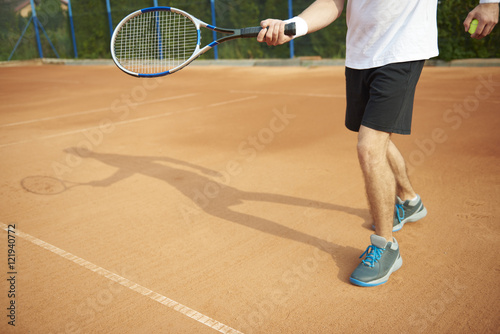 Shadow of tennis player on the court. © gpointstudio