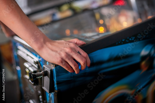 Young woman playing on the pinball machine photo