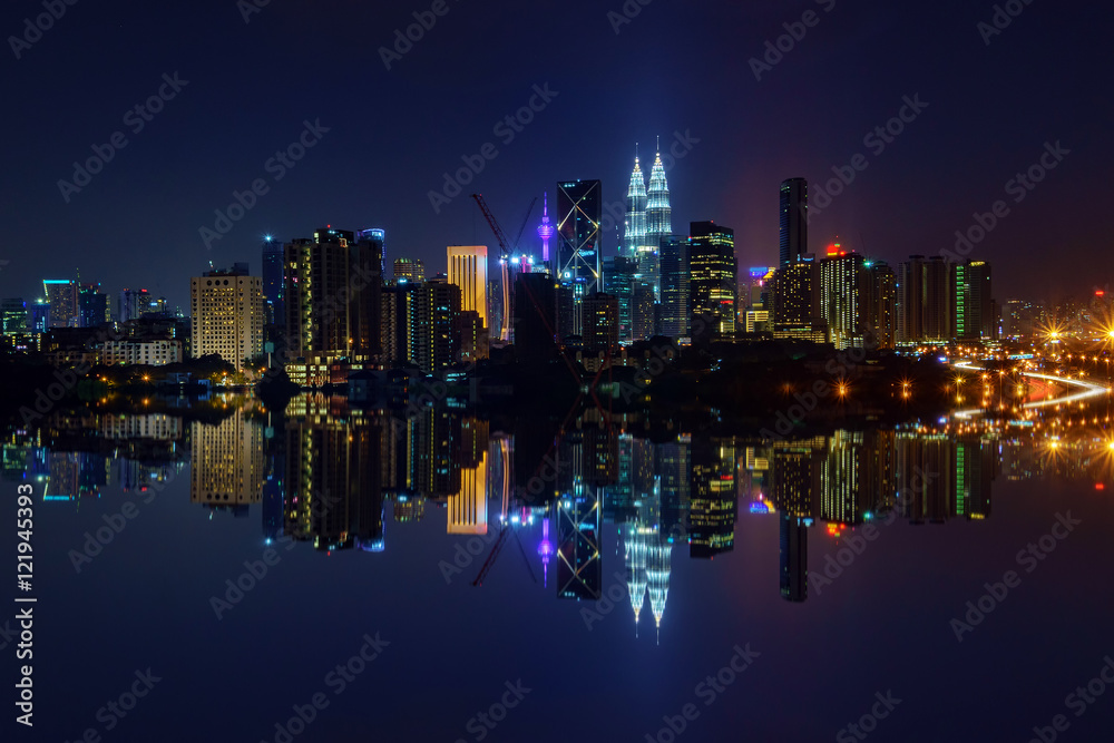Majestic view of Kuala Lumpur city skyline at night with full reflection.