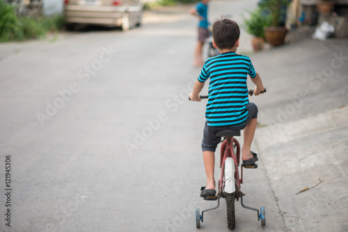 Little boy riding bicycle on the road around the house