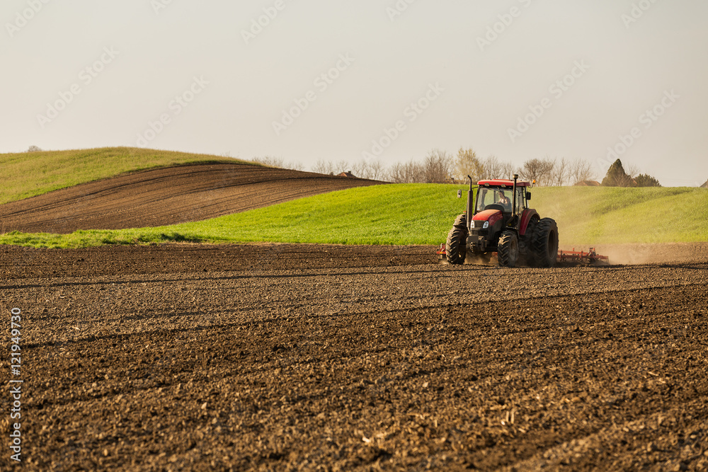 Farmer in tractor preparing land with seedbed cultivator Farmer in tractor preparing land with seedbed cultivator