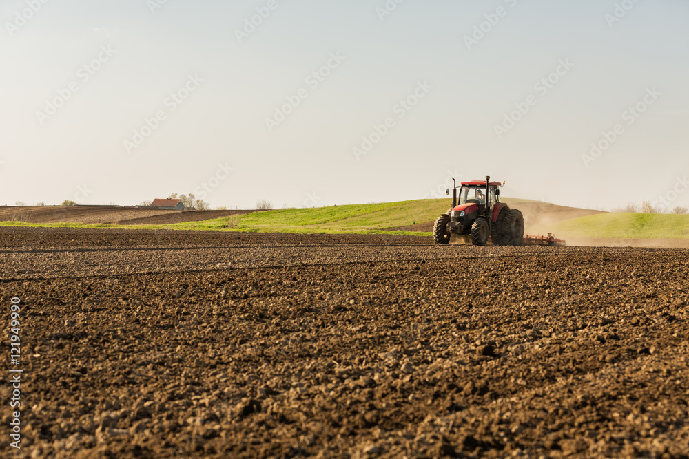 Farmer in tractor preparing land with seedbed cultivator Farmer in tractor preparing land with seedbed cultivator
