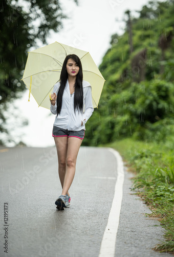 Woman with yellow umbrella alone as raining