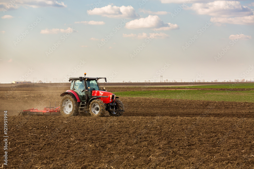 Fototapeta premium Farmer in tractor preparing land with seedbed cultivator