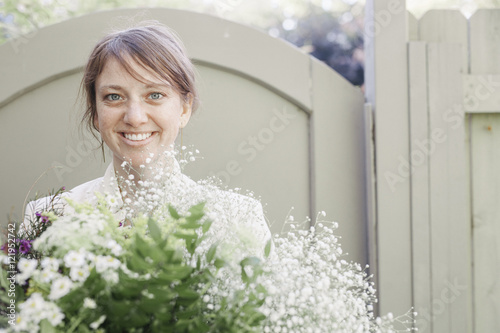 Portrait of a smiling woman carrying a bunch of white flowers.