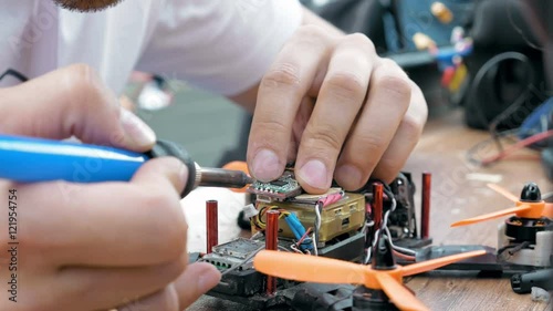 Close up of man's hands welding details while assembling FPV drone using tools, preparing quadcopter for flight. Repair drone before training process.