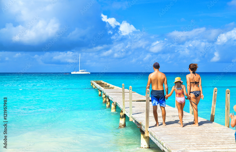 Back view of a happy family on tropical beach. Family standing on a wooden pier.