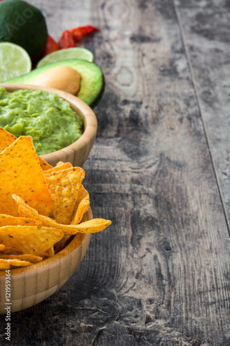 Nachos, guacamole and ingredients on wooden table