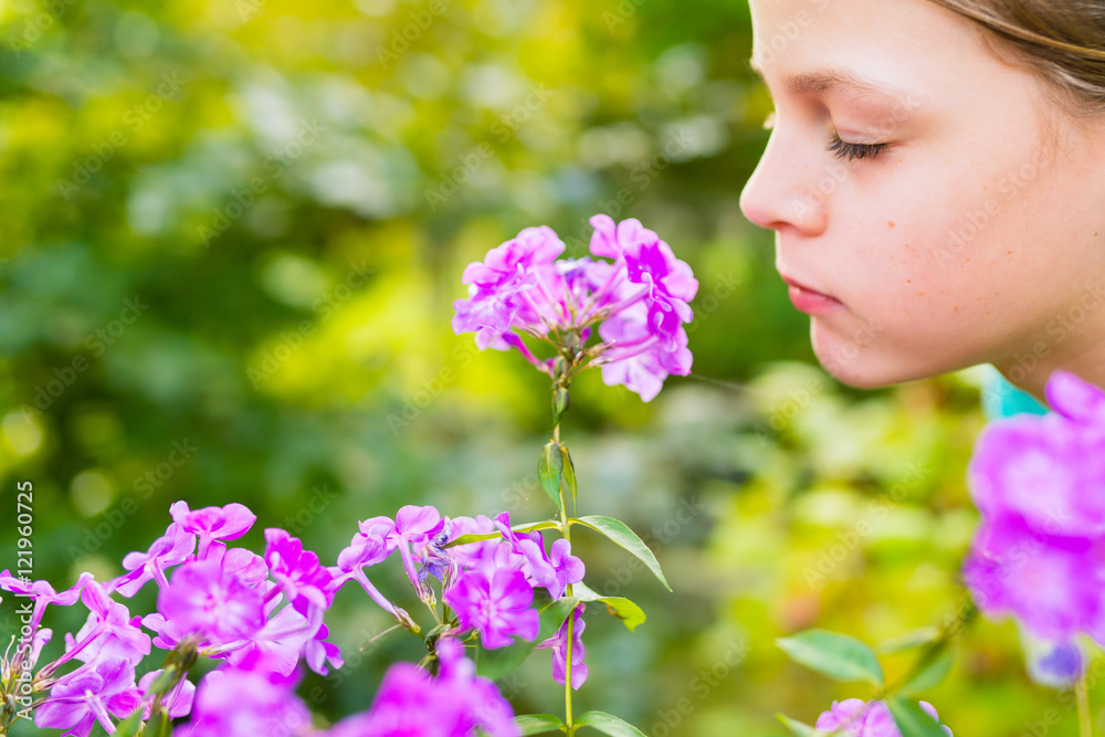Young beautiful girl smells purple flowers in the garden - shallow depth of field Young beautiful girl smells purple flowers in the garden - shallow depth of field