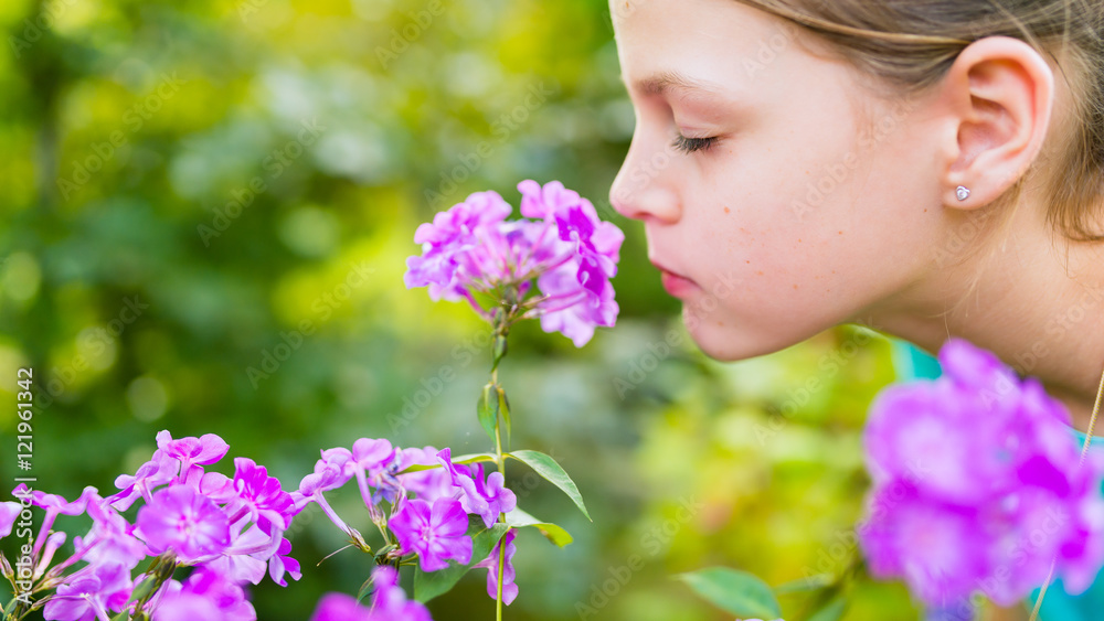 Young beautiful girl smells purple flowers in the garden - shallow depth of field Young beautiful girl smells purple flowers in the garden - shallow depth of field