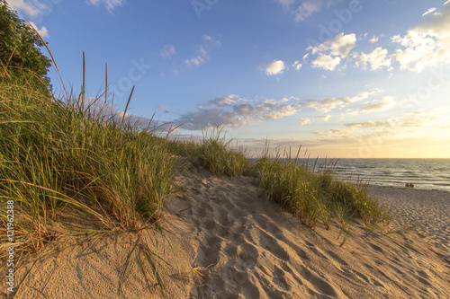 Warm Summer Breeze. Sunny afternoon day at the beach with a sand dune in the foreground and the beginnings of a sunset at the water s horizon. Hoffmaster State Park  Michigan.