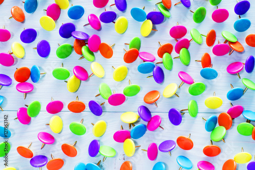 Colorful push pins on blue wooden background, close up. Bright multi-colored thumbtacks. Background with a pushpin.