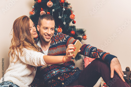 Young couple under christmas tree having fun. photo