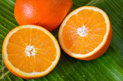 Fresh oranges cut in half on green banana leaf background