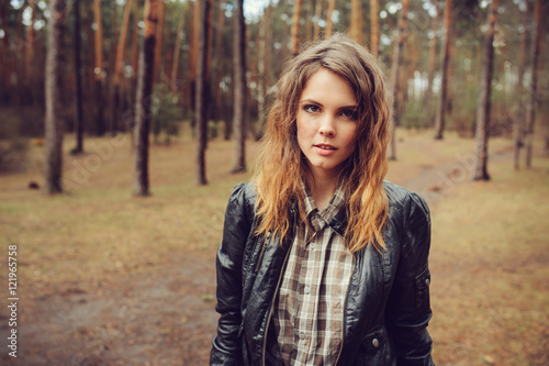 autumn outdoor portrait of young beautiful woman with natural makeup in leather jacket and plaid shirt, soft vintage toned © mashiki