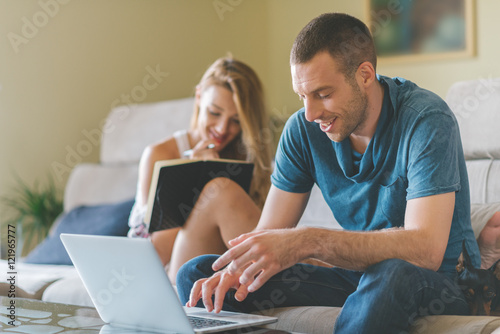 Young smiling couple working at home  with laptop and smartphone.