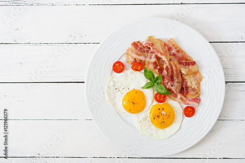 English breakfast - fried egg, tomatoes and bacon. Top view.