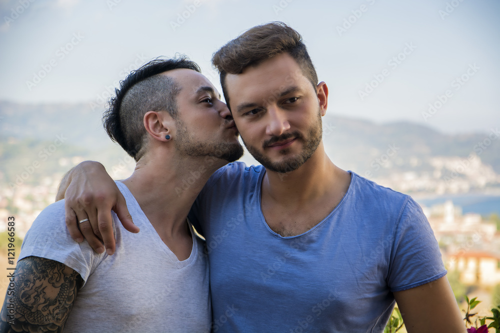 Young man kissing his partner outdoors Young man kissing his partner outdoors