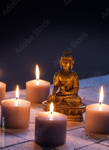 bronze Buddha with warm lighted candles for concept of mindfulness