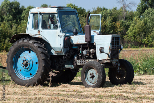 Old tractor in summer on field.