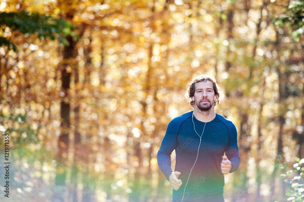Fototapeta premium Young handsome runner outside in sunny autumn nature