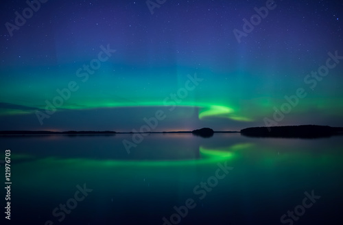 Northern lights dancing over calm lake in Sweden © Conny Sjostrom