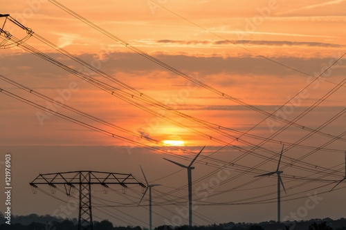 Electricity pylons and lines at dusk, Silhouette electricity pylons during sunrise. and wind power plant