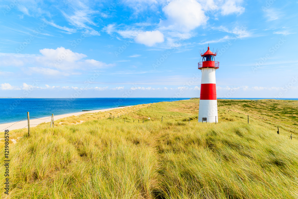 Ellenbogen lighthouse on sand dune against blue sky with white clouds on northern coast of Sylt island, Germany