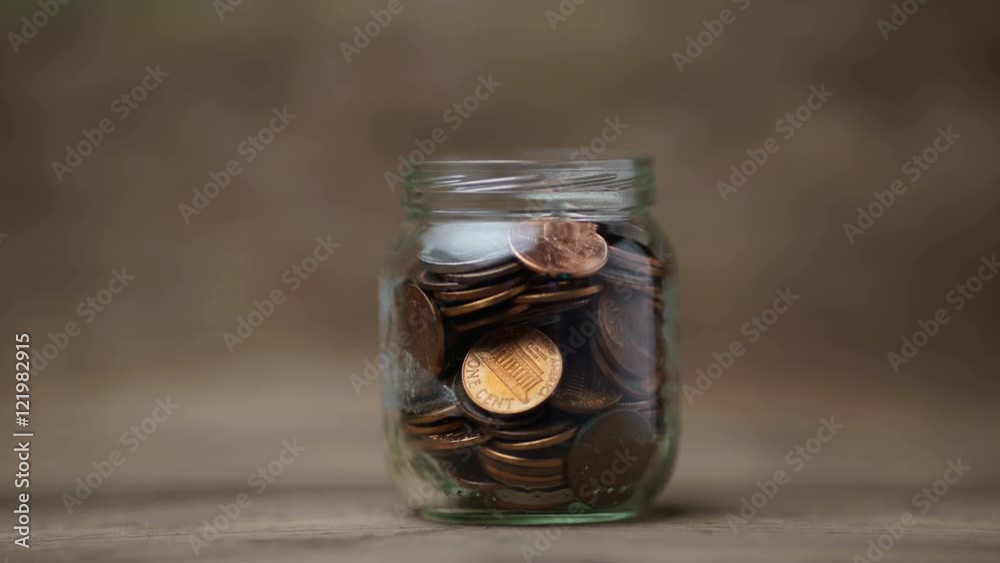 Glass jar being filled with coins, stop motion footage Glass jar being filled with coins, stop motion footage
