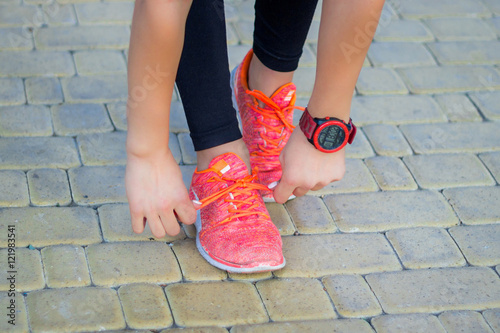 Young fitness girl ties up sneakers laces preparing for running