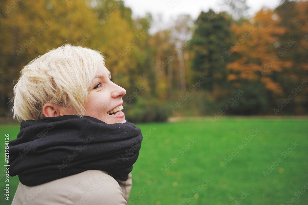 Portrait of smiling cute blonde on a background autumn forest closeup in profile Portrait of smiling cute blonde on a background autumn forest closeup in profile