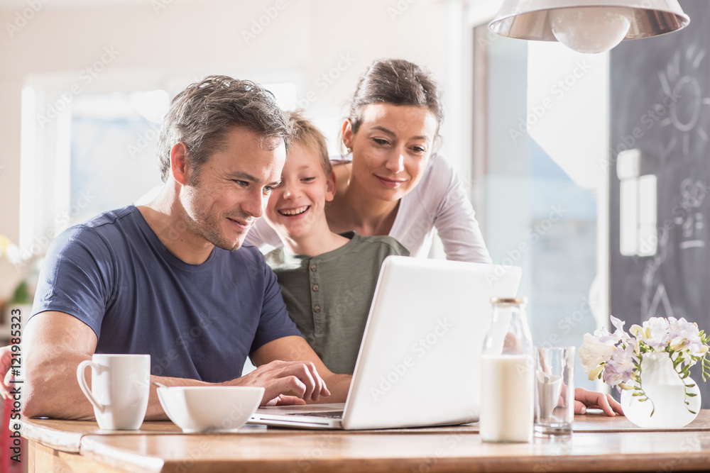 A family using a laptop while having breakfast in the kitchen A family using a laptop while having breakfast in the kitchen