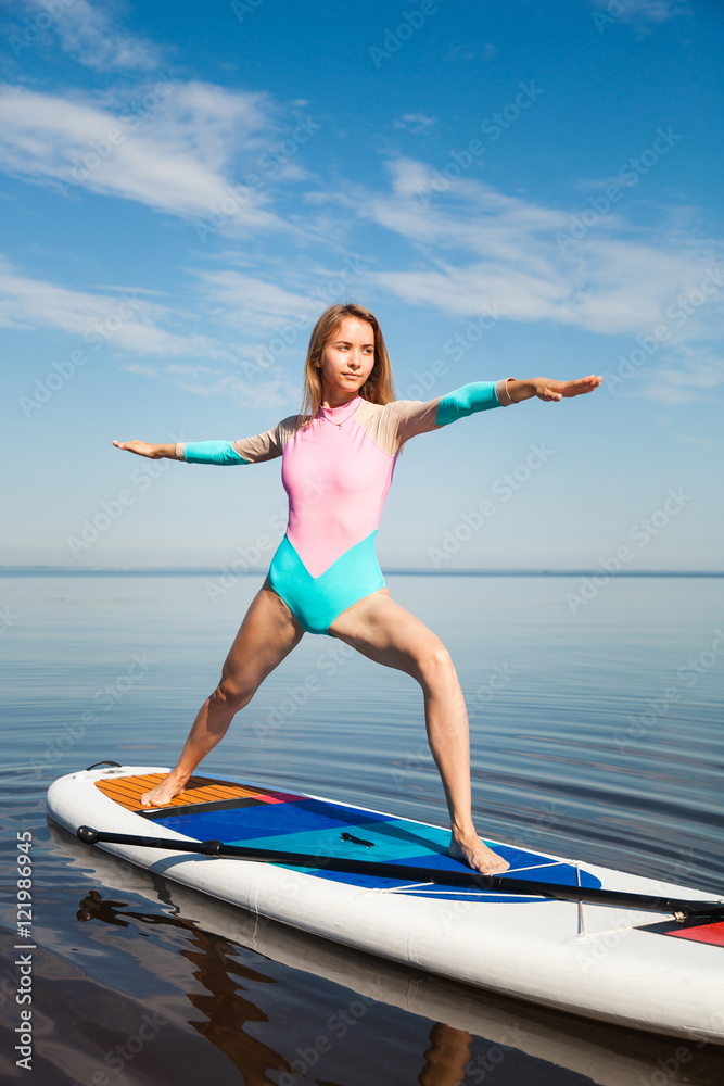 Woman doing yoga on sup board with paddle Woman doing yoga on sup board with paddle
