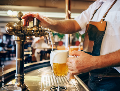 Bartender pouring the fresh beer in one of Czech traditional pub photo