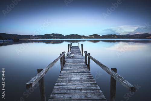 Fototapeta Wooden pier or jetty on a blue lake sunset and sky reflection on