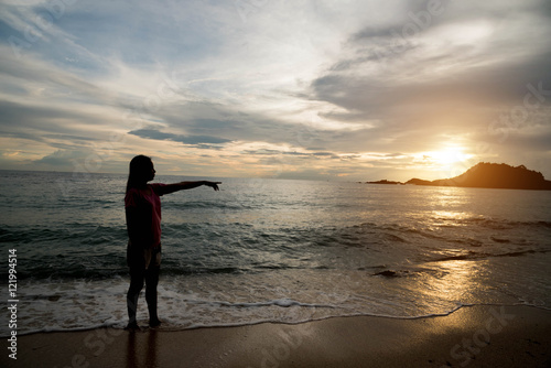 Young woman Standing, pointing to the sky on a sandy beach © stcom
